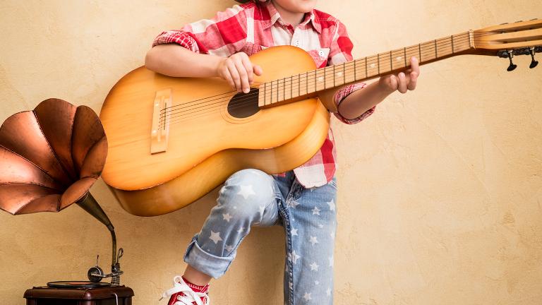 Kid listen music at home. Hipster child with retro vintage acoustic guitar