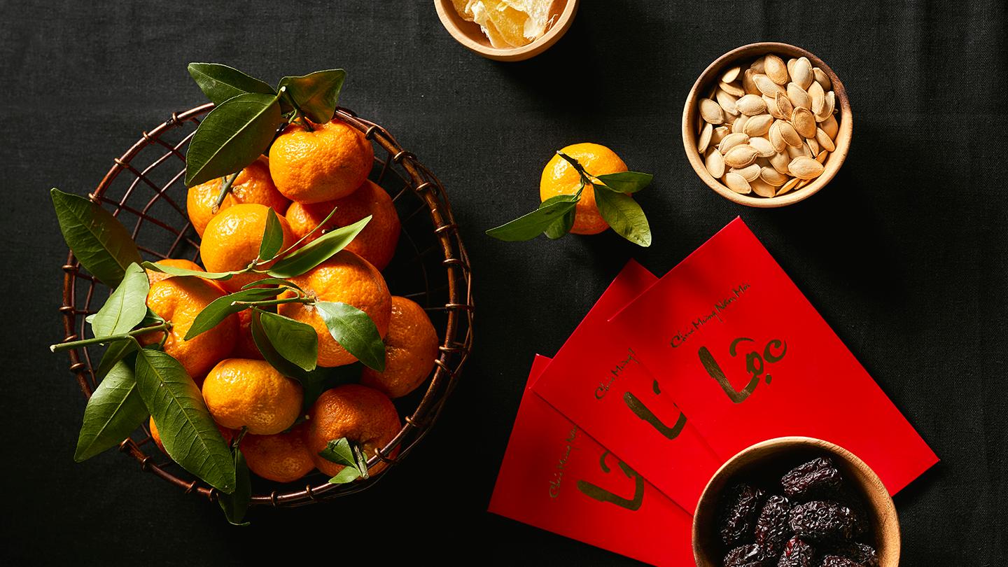 Group of colorful Vietnamese jam for Vietnam Tet holiday, also lunar new year of Asia, traditional preserved fruit from jujube, ginger jam and pumpkin seeds, tangerine. Text on envelop means Happy New Year and Happiness.